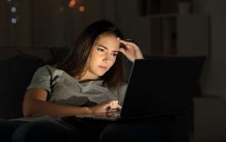 Image of a woman using a laptop in the night to accompany article "To succeed with a contravention – get the detail right" by Michael Lynch Family lawyers