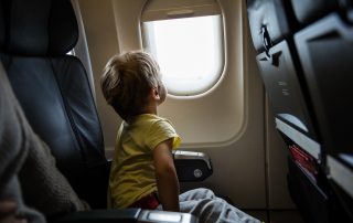 A photo of a little boy looking out of window in an airplane