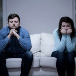 A photo of a couple after argument sitting on the sofa