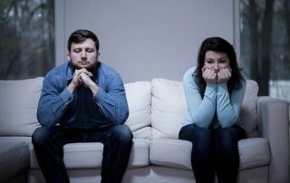 A photo of a couple after argument sitting on the sofa