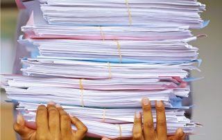 A photo of a person carrying a pile of documents