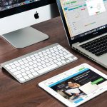 A stock photo of two computers and one tablet on one desk