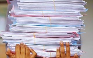 A stock photo of a person carrying a pile of documents and files
