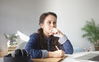 A photo of a school girl sitting at her desk, thinking