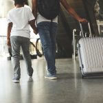 A stock photo of a child holding his father's hand, at the airport.