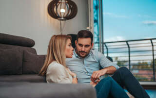 Image of a couple at home talking, accompanying the family law article "Are you in a defacto relationship?"