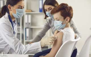 Image of a doctor preparing to vaccinate a child, accompanying family law article "Vaccinations for Children"