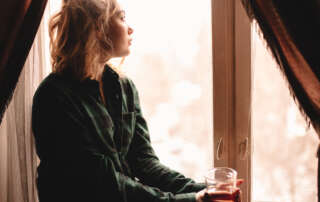 Image of a woman drinking tea and looking through window