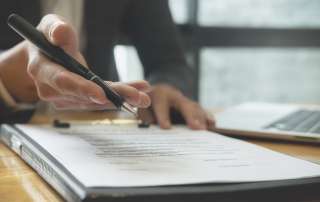 Image of a person's hand with a pen, accompanying family law article "Ensure your evidence is accurate"